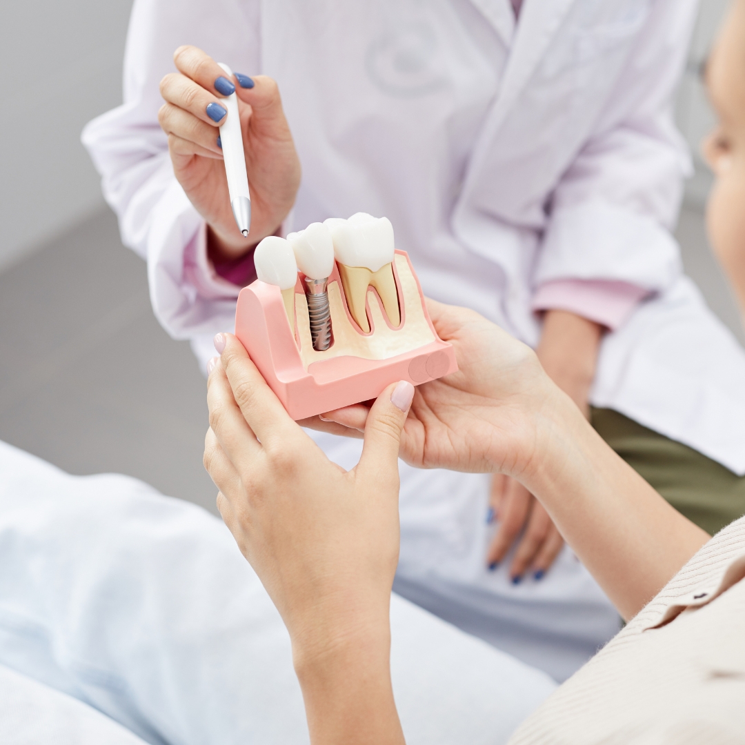 Dentist explaining a dental implant model to a patient in Guildford
